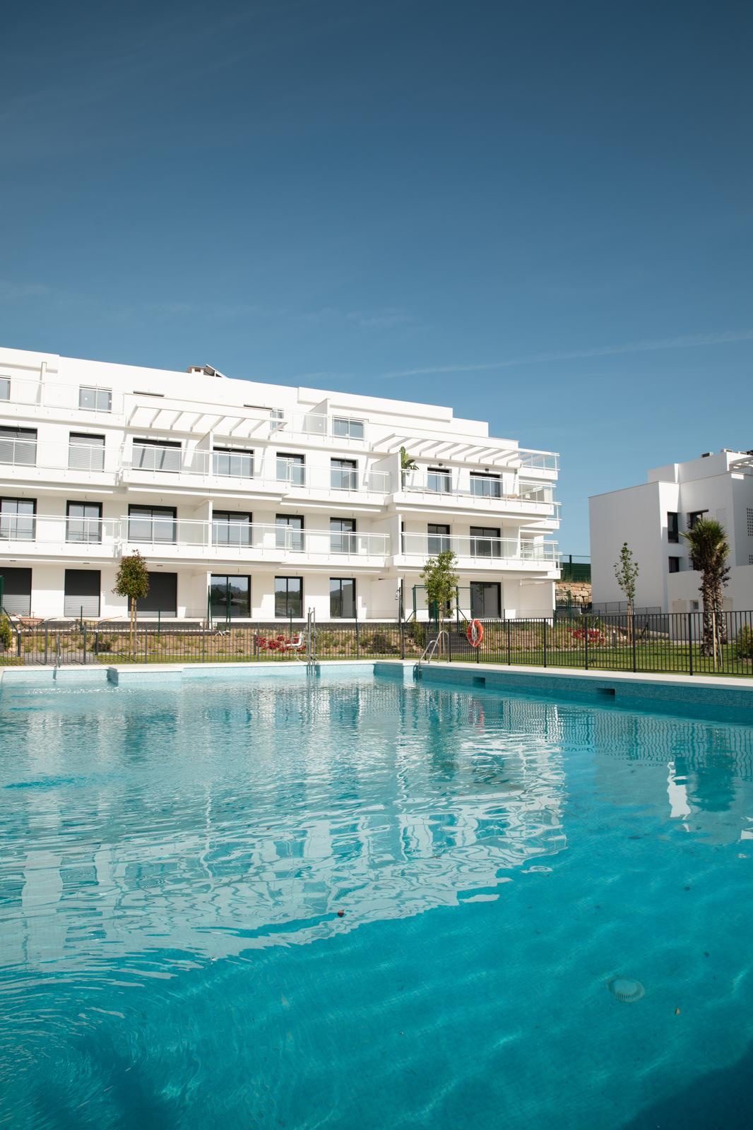 Zwembad voor het witte appartementsgebouw onder een strakblauwe lucht